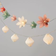 some paper flowers are hanging from a string with lights on it and one flower is in the center