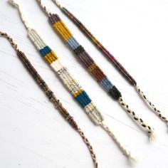 three beaded bracelets are lined up on a white surface, one is multicolored