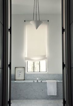 a bathroom with a large window and white tile flooring, along with a bathtub