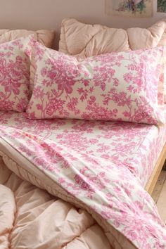 a bed with pink and white pillows on top of it