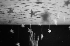 a hand reaching up towards stars hanging from the ceiling