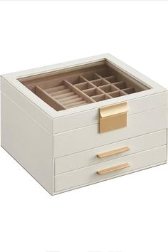 a white box with two drawers and gold handles on the bottom is open to reveal an empty drawer