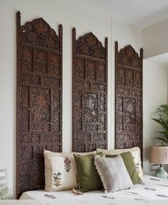 a bed with pillows and decorative wooden headboard