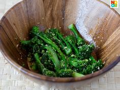 a wooden bowl filled with broccoli on top of a table