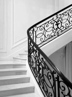 a black and white photo of a staircase with wrought iron handrail on the bottom