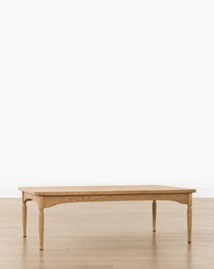 a wooden table sitting on top of a hard wood floor next to a white wall