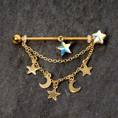 a gold plated barbell ring with stars and moon charms attached to the end