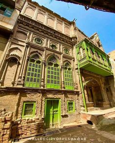 an old building with green doors and windows in the middle of it's courtyard