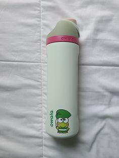 a green and pink water bottle sitting on top of a bed