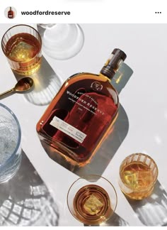 a bottle of whisky sitting on top of a table next to glasses and spoons