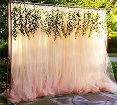 an outdoor wedding ceremony with greenery hanging from the ceiling and draped in pink tulle