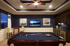 a pool table in the middle of a living room with two pictures on the wall