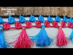 some tassels are hanging on the wall with blue and pink yarn in them