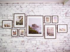 a white brick wall with many pictures hanging on it