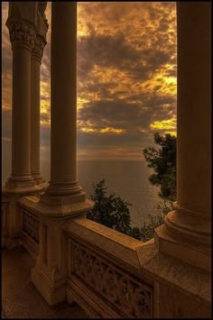 the sun is setting over an ocean and some pillars with columns on each one side