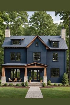 a large blue house with lots of windows on the front and side of it, surrounded by trees