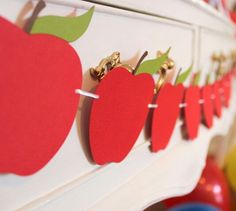 an apple themed wall hanging on the side of a white dresser in a child's room