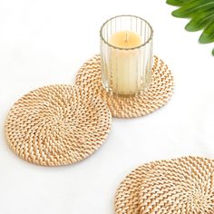 two wicker coasters next to a candle on a table