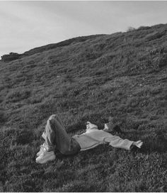 a person laying in the grass on top of a hill