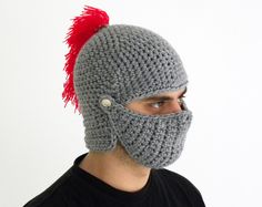 a man wearing a crocheted helmet with a red pom - pom