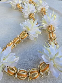 white and gold flowers are arranged on a table cloth with beads in the shape of bells