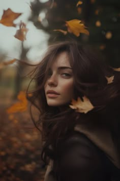 a woman with long hair standing in leaves