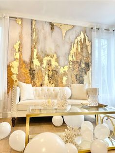 a living room filled with white balloons and gold foil paint on the wall behind it