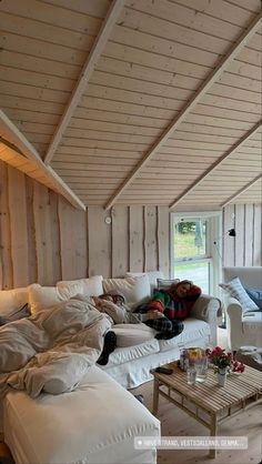 a living room filled with lots of white furniture and pillows on top of couches