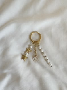 a gold keychain with pearls and stars hanging from it on a white sheet