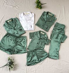 four pieces of green and white clothing laid out on a bed next to some flowers