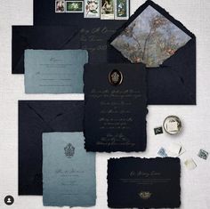 an assortment of black and blue wedding stationery with envelopes, stamps, and rings