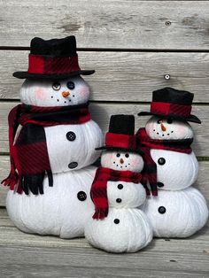 four snowmen wearing hats and scarves sitting on a bench