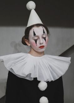 a woman with white makeup and clown make - up on her face wearing a black dress