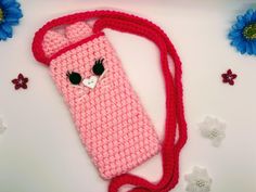 a crocheted pink cell phone case with a cat on the front and side