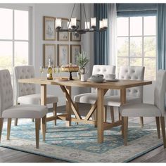 a dining room table with white chairs and a blue rug