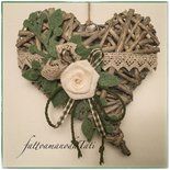 a white rose is placed in the shape of a heart with green leaves and ribbons