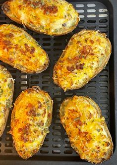 six baked potatoes with cheese and seasoning on top in a black grill grate