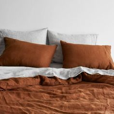 an unmade bed with brown linens and pillows