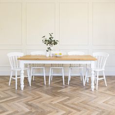 a white table with four chairs and a potted plant