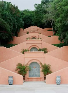 a pink building with palm trees in the background