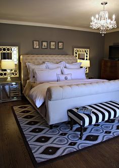 a bedroom with a large bed and chandelier in the corner, along with a black and white rug