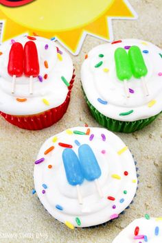 cupcakes with white frosting and colorful pops on them