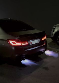 two cars parked next to each other in a parking lot at night with lights on