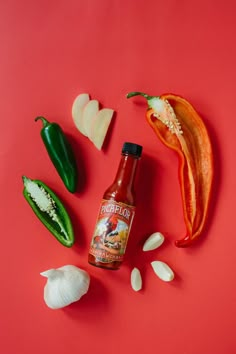 an assortment of hot sauces and vegetables on a red surface