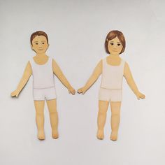 two paper dolls are holding hands and standing next to each other on a white surface