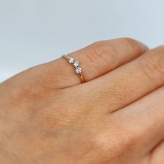 a woman's hand with a diamond ring on top of her finger, showing the side view