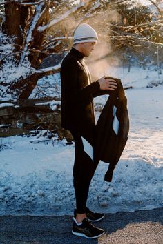 a man standing in the snow holding his jacket