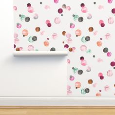 a white wall with pink and green watercolor spots on it next to a wooden floor