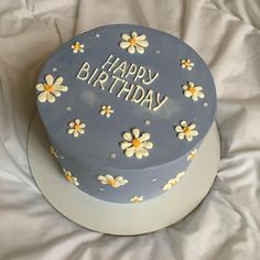 a blue birthday cake with white and yellow flowers