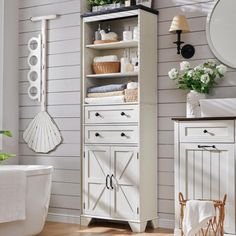 a bathroom with white walls and wooden floors, an old fashioned cabinet is next to the bathtub